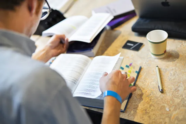 Student som sitter och läser bok. Foto.